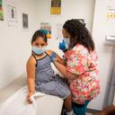 A child receives a vaccine from a nurse.