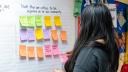 A woman in Berks County puts up a Post It note listing issues critical to her community as part of a yearlong Spotlight PA study.