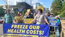Healthcare-cost rally outside Geisinger, with participants holding signs and a banner reading “FREEZE OUR HEALTH COSTS!