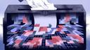 Illustration of a hand inserting a white ballot into a dark ballot box filled with colorful geometric shapes.