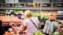 A woman browses produce at a grocery store.