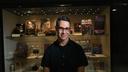 Adam Lowenstein stands in front of a display case of horror artifacts.