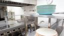 A stock image of plates stacked on a stainless steel shelf in a kitchen