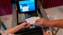 A polling judge, right, helps guide a voter's ballot into a voting machine during the Pennsylvania primary election, at Mont Alto United Methodist Church in Alto, Pa., on May 17, 2022.