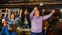 A woman and a man raise their arms in celebration as people around them clap.