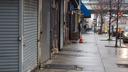 A man standing on the sidewalk on 52nd Street is surrounded by local business’s that are closed due to the coronavirus outbreak on Saturday, March, 28, 2020.