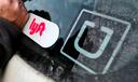 In this 2018, file photo, a Lyft logo is installed on a car next to an Uber sticker in Pittsburgh.