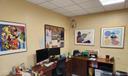 An office with four pieces of art on the walls
