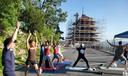People in yoga poses in front of Reading Pagoda, which is surrounded by scaffolding. 