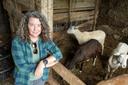 A woman stands next to an enclosure with sheep