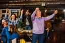 A woman and a man raise their arms in celebration as people around them clap.