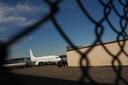 An airplane and a building seen through a chain link fence.