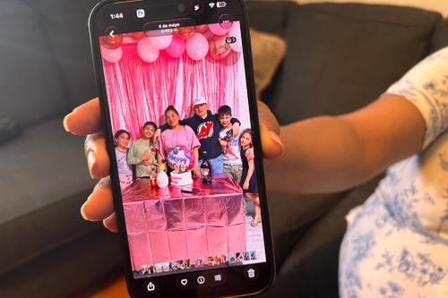 Wendys Martinez holds up her cell phone showing a photo of her husband, Carlos Moreno, and their children.