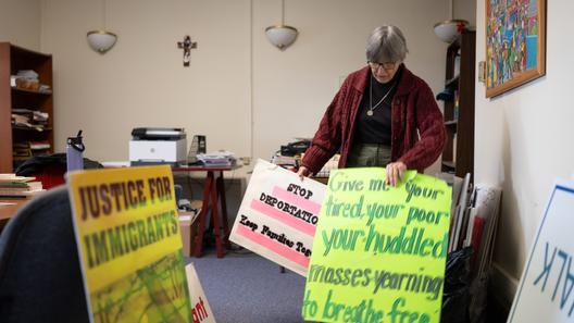 Sister Anne McCarthy with the Benedictine Sisters of Erie looks through her signs protesting President Donald Trump’s nationwide immigration crackdown.