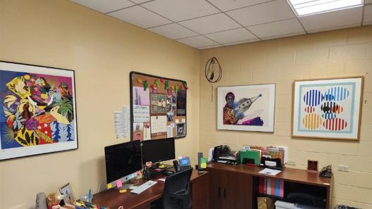 An office with four pieces of art on the walls