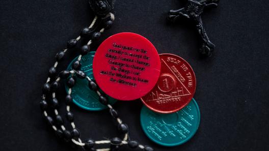 A photo of a rosary and sobriety chips.