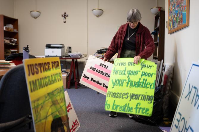 Sister Anne McCarthy with the Benedictine Sisters of Erie looks through her signs protesting President Donald Trump’s nationwide immigration crackdown.
