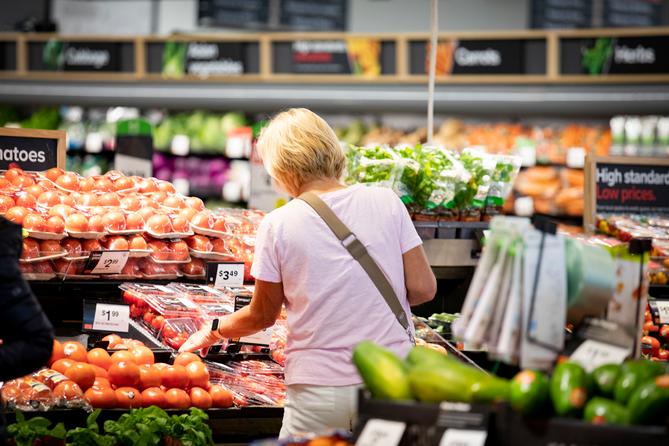 A woman browses produce at a grocery store.