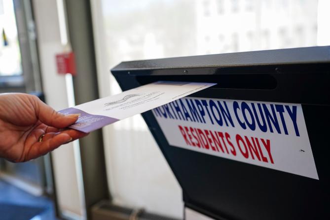 A voter puts a ballot into a drop box on primary Election Day 2024 at Bethlehem City Hall in Northampton County, PA.