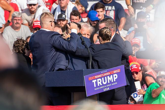 The Secret Service immediately surround former President Donald Trump after he was shot during his campaign stop at the Butler Farm Show grounds.