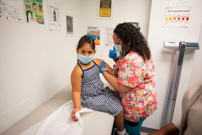 A child receives a vaccine from a nurse. A child receives a vaccine from a nurse.
