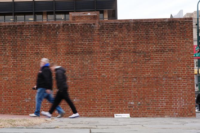 People walk past locations of the now removed explanatory panels that were part of an exhibit on slavery.
