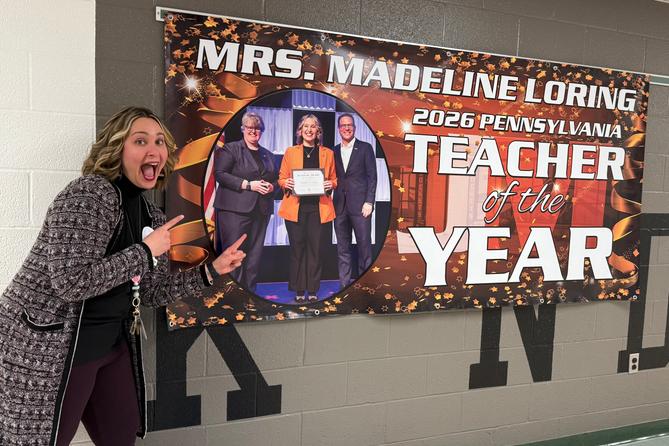 Madeline Loring poses with a sign celebrating her Teacher of The Year Award.