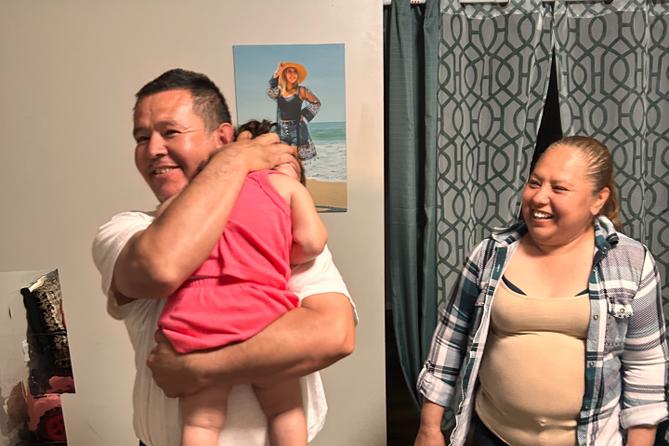 Erasmo Zavala hugs his granddaughter, Selene, as his wife Maria stands nearby. A picture of Selene’s mother, Selena, who was murdered, hangs behind the family. May 29, 2026.