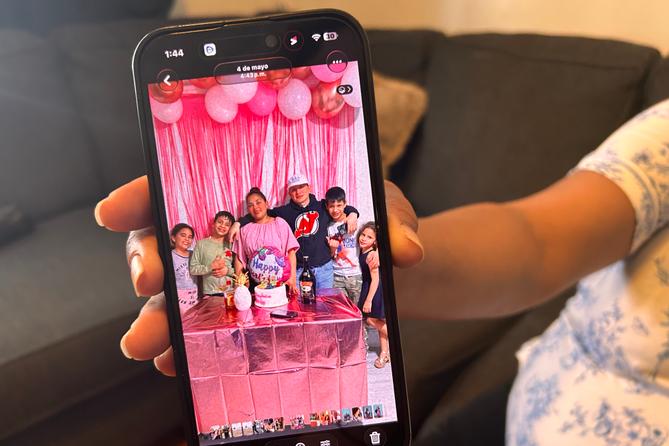 Wendys Martinez holds up her cell phone showing a photo of her husband, Carlos Moreno, and their children.