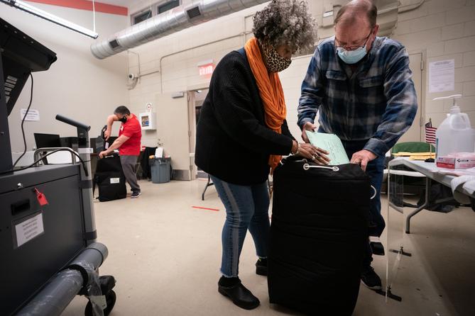 Three election workers put provisional ballots in the hopper at the 5th and 9th division of the 26th Ward after the polls closed at the polling place at Barry Recreation Center, in South Philadelphia, on Election Day.